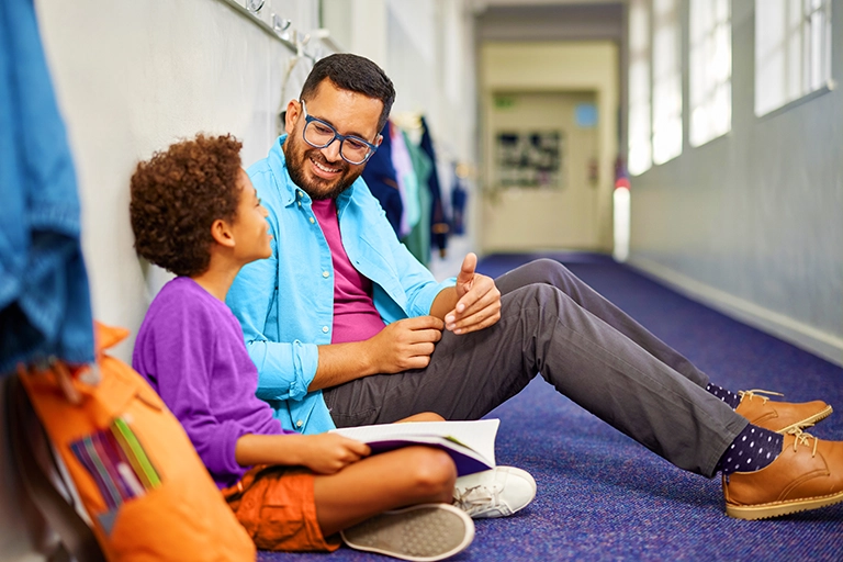 Teacher sitting on the floor talking with a student