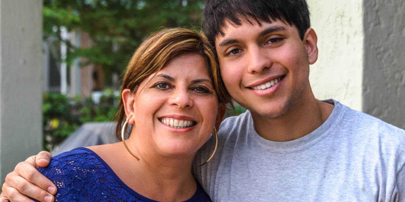 Hispanic teenager and his mom smiling