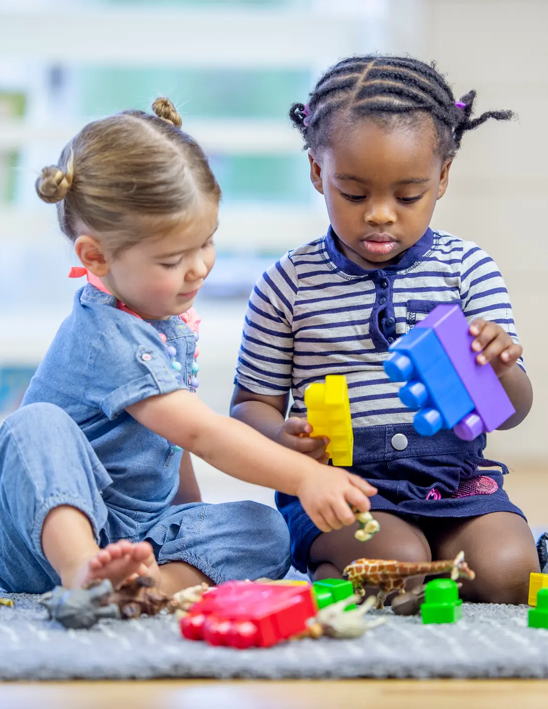 Two toddlers playing with blocks